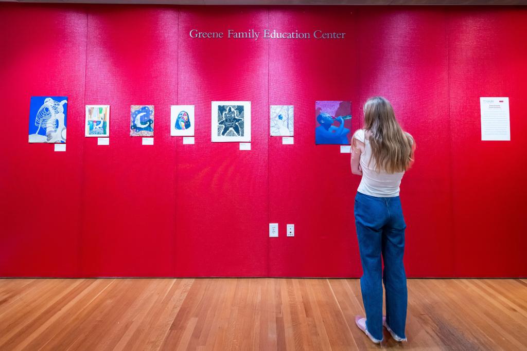 High Museum patron viewing multiple small paintings in a row 