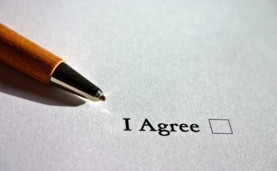 Close-up of a pen lying on paper with "I agree" checkbox